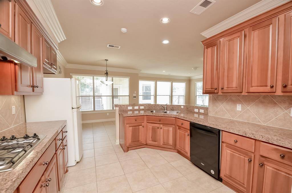 Expansive kitchen featuring abundant cabinetry, a brand-new refrigerator upon move-in, and a convenient dry bar.