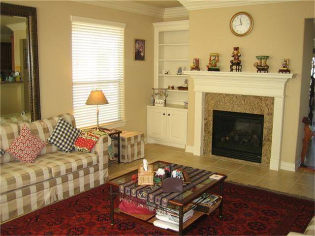 Cozy family room featuring a built-in shelving unit and elegant fireplace.
