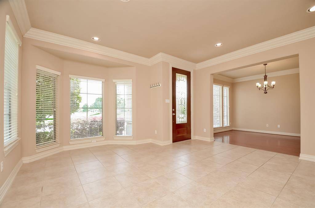 Elegant formal living area with abundant natural light and stylish tile flooring, perfect for entertaining or relaxing.