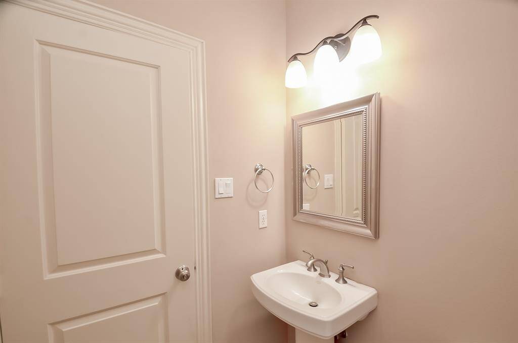 Stylish guest bathroom with elegant lighting and a classic pedestal sink.