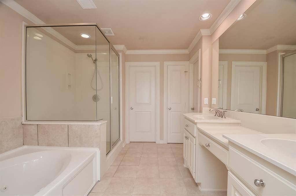 Spacious formal bath featuring a large closet, dual sinks, and a sleek shower.