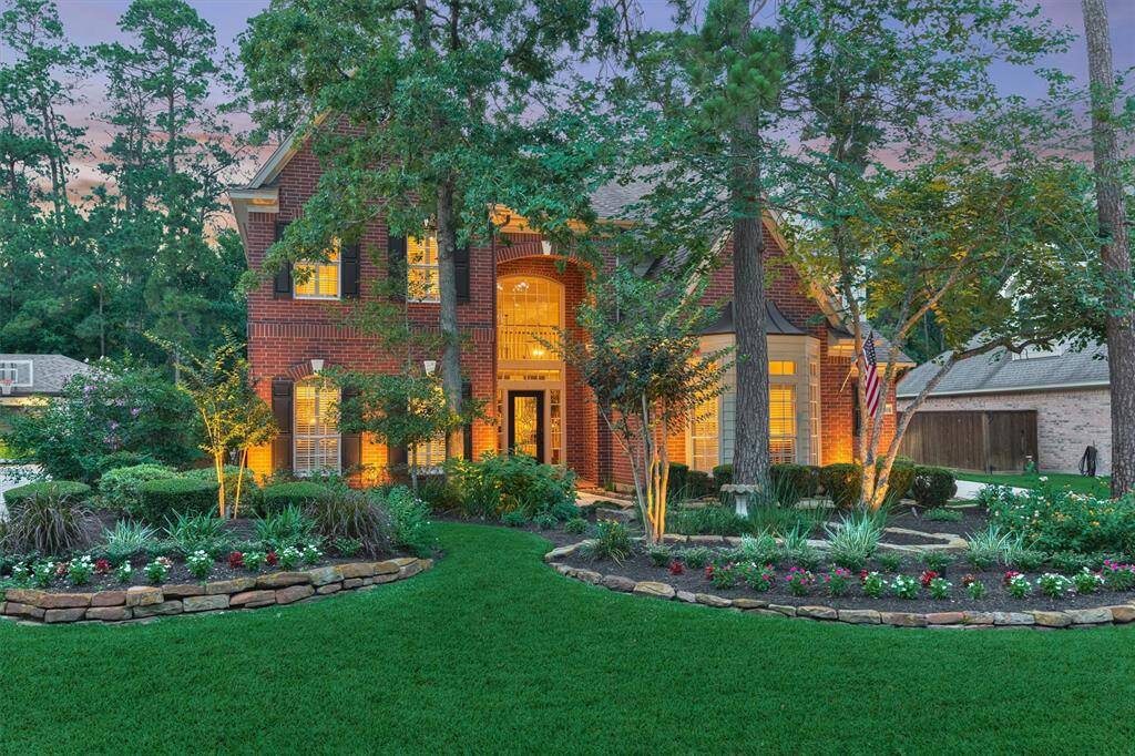 This beautiful two-story brick home is set amidst lush trees and vibrant landscaping. It features a welcoming and manicured front yard offering a serene and inviting curb appeal.