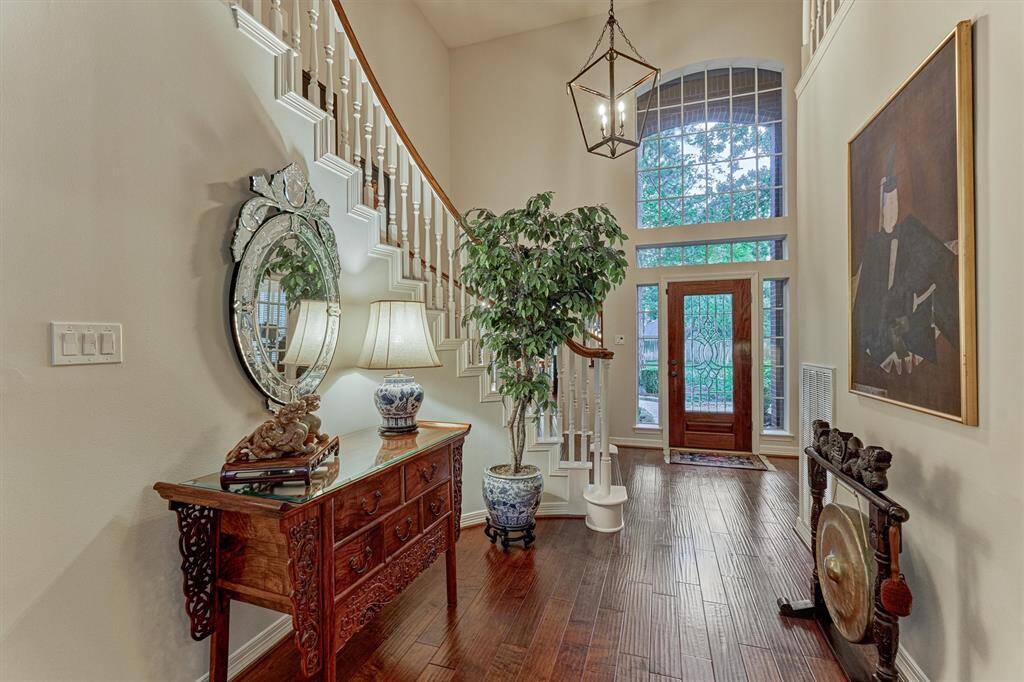 This elegant entryway features a grand staircase, high ceilings, and abundant natural light from large windows.