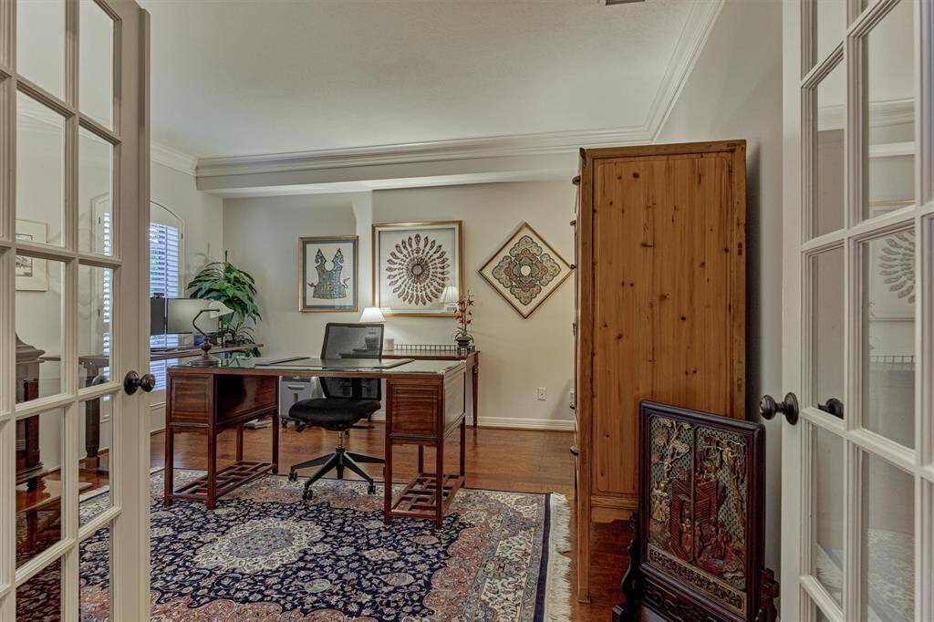 This photo showcases a well-lit home office with a classic and elegant design. The room is accessed through French doors, and large windows provides natural light.