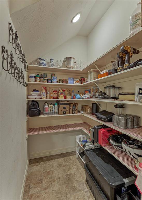 This generous-sized pantry features ample shelving for organized storage, perfect for keeping food, kitchen essentials and small appliances neatly arranged.