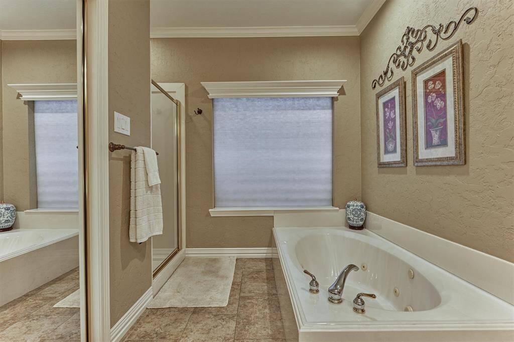 This bathroom features a luxurious jacuzzi tub, separate shower, and tasteful appointments. The neutral tones and ample natural light create a calming and inviting space.
