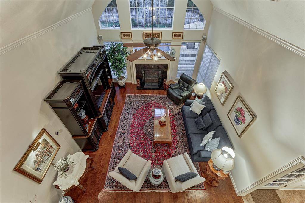 This spacious living room features high ceilings, large windows for natural light, and a cozy fireplace. It boasts elegant hardwood floors, and comfortable seating space, making it perfect for relaxation and entertaining.