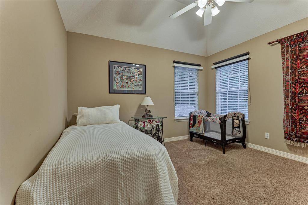 Another secondary bedroom with neutral walls, two windows with blinds, and a ceiling fan with lighting.