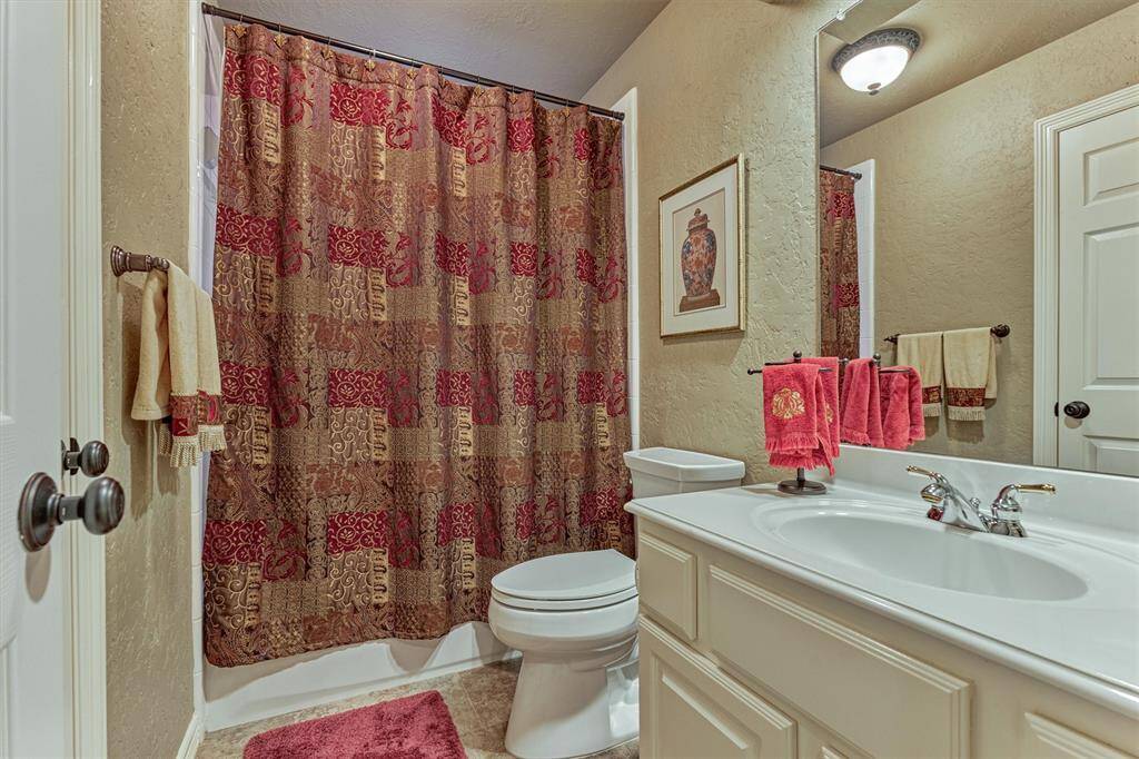 This secondary bathroom features a classic design with a white vanity with ample counter space, and warm wall tones.