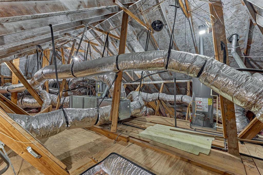 This photo shows a spacious attic with wood floor decking. This area is organized and accessible, perfect for storage and maintenance work.