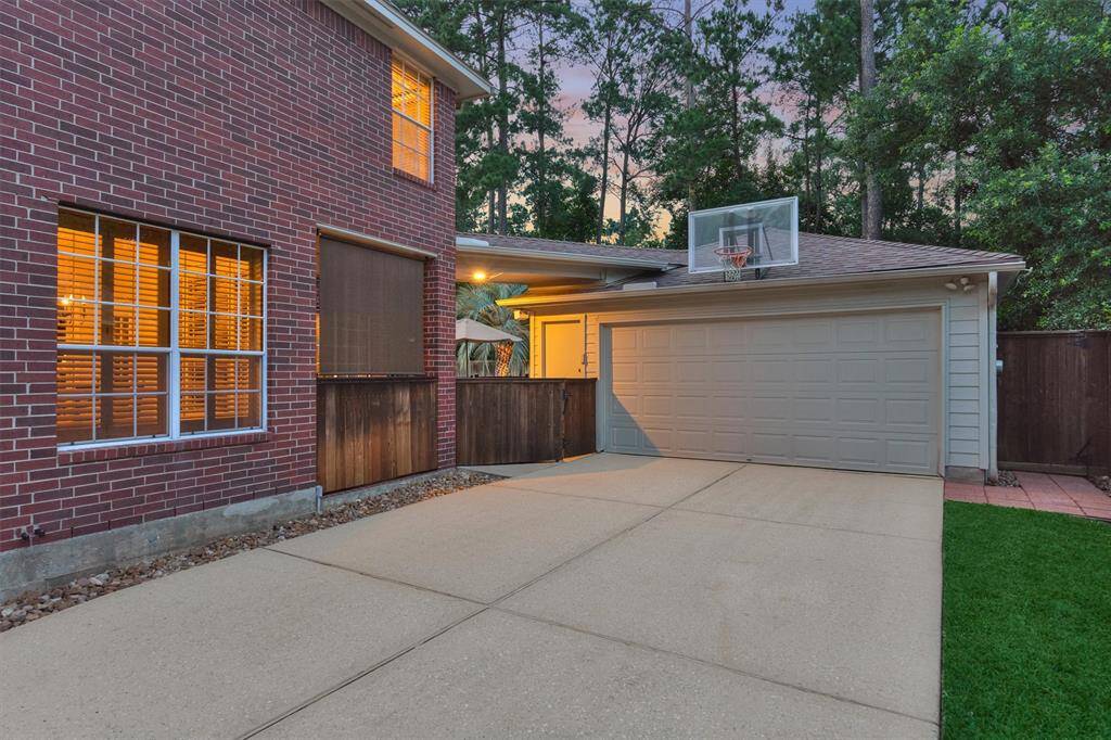This photo shows a spacious driveway leading to a two-car garage with extension, and the cozy back covered porch.
