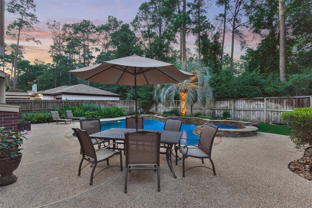 This backyard features a spacious patio with an beautiful in-ground pool and spa and lush greenery, providing a private and serene outdoor retreat.