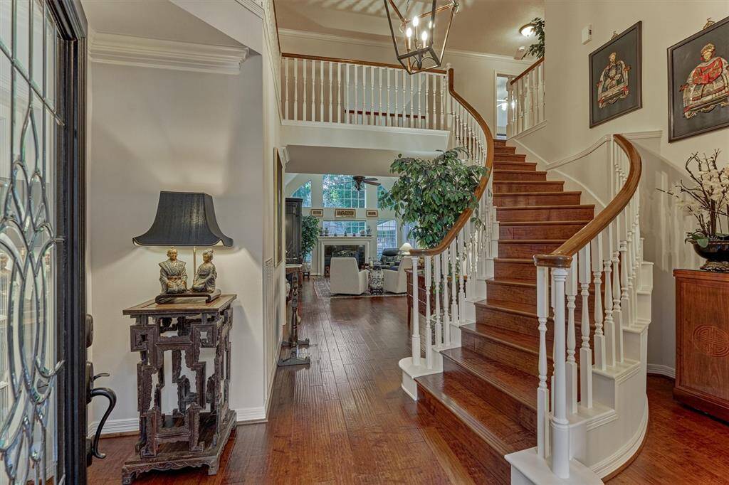 This inviting two-story entryway features a grand, curved staircase leading to an open living area.
