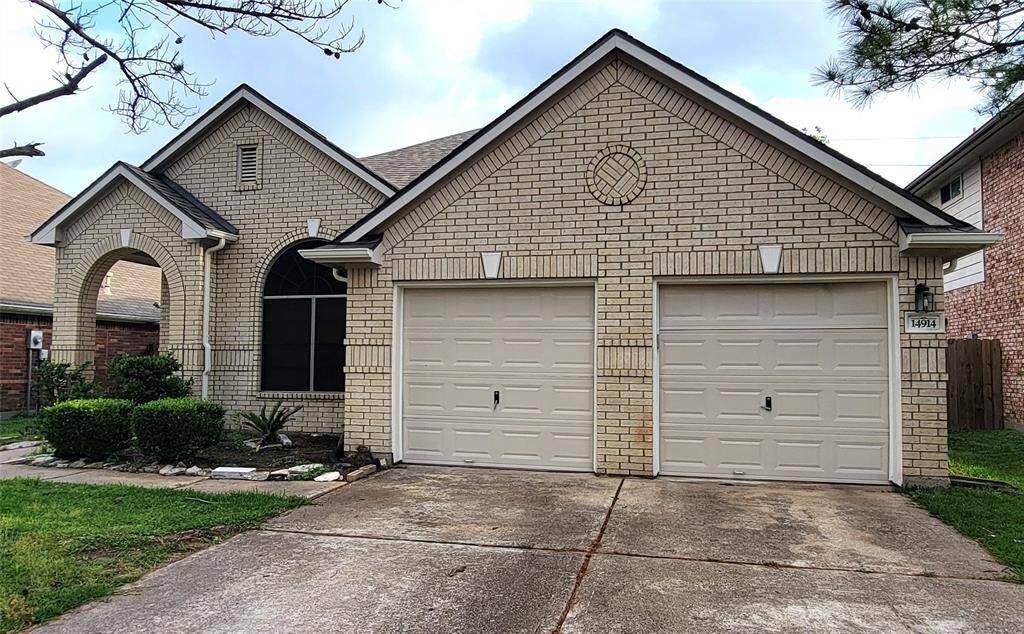 A welcoming front view with a classic brick facade, well-kept lawn, and a spacious driveway leading to a two-car garage. The curb appeal is enhanced by mature trees and a clean, inviting entryway.