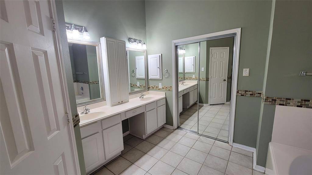 The en-suite bathroom includes a vanity with storage, a full-size mirror, and a shower/tub combination—offering both functionality and convenience.