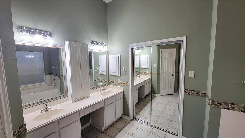 The en-suite bathroom includes a vanity with storage, a full-size mirror, and a shower/tub combination—offering both functionality and convenience.