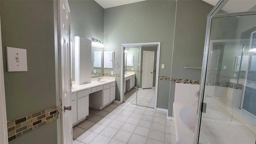 The en-suite bathroom includes a vanity with storage, a full-size mirror, and a shower/tub combination—offering both functionality and convenience.
