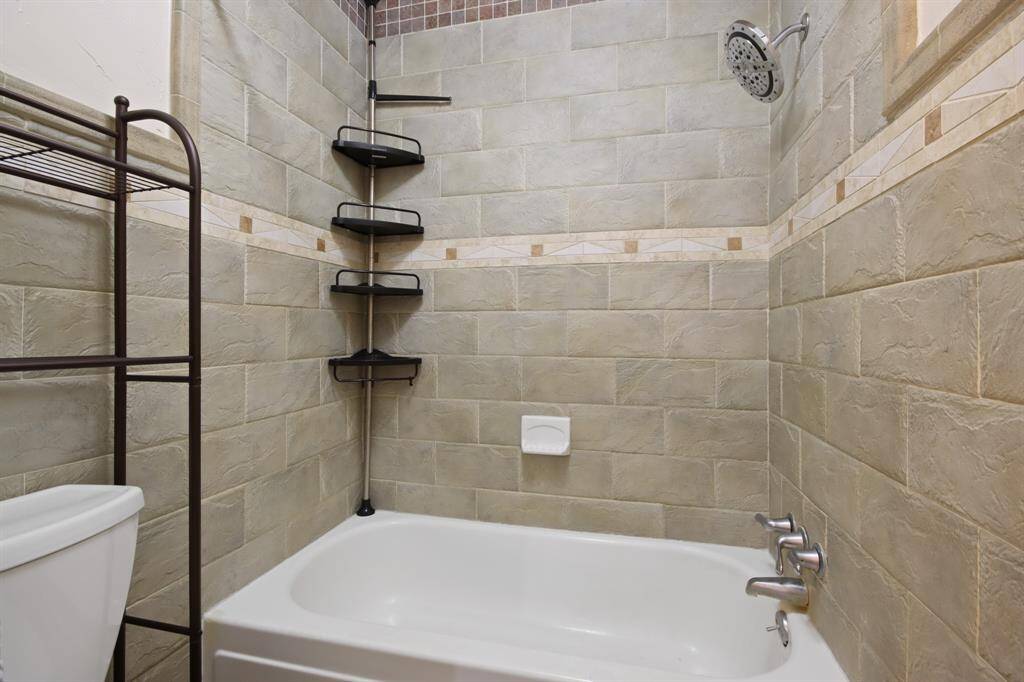 Worthy bathroom retreat featuring a garden tub and shower combo, beautifully accented by an elegant stone wall.