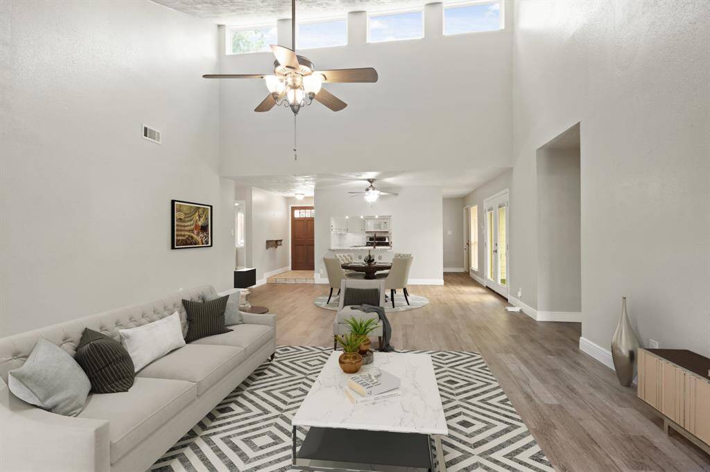 Virtually Staged: This lovely living room is open and bright! Featuring high ceilings, beautiful wood tile floors, a ceiling fan, and plenty of natural light throughout these stunning high windows.