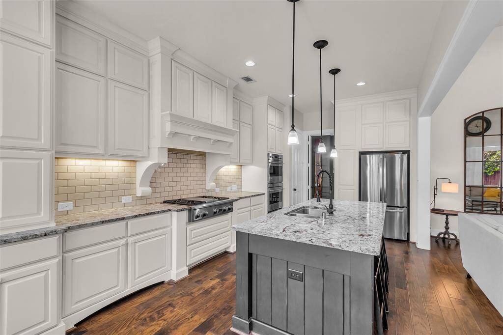 Large island with bar stool seating, under cabinet lighting, double ovens