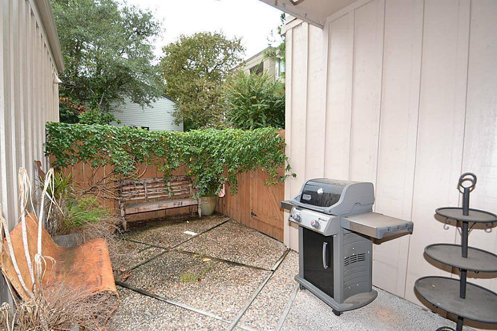 Cozy outdoor patio with a grill, bench, and greenery, perfect for relaxing and entertaining.