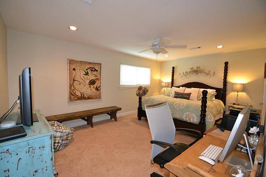 Spacious bedroom with a cozy atmosphere, featuring a large bed, ample natural light, and a small work desk. The room includes warm lighting and decorative touches, creating a comfortable and inviting space.