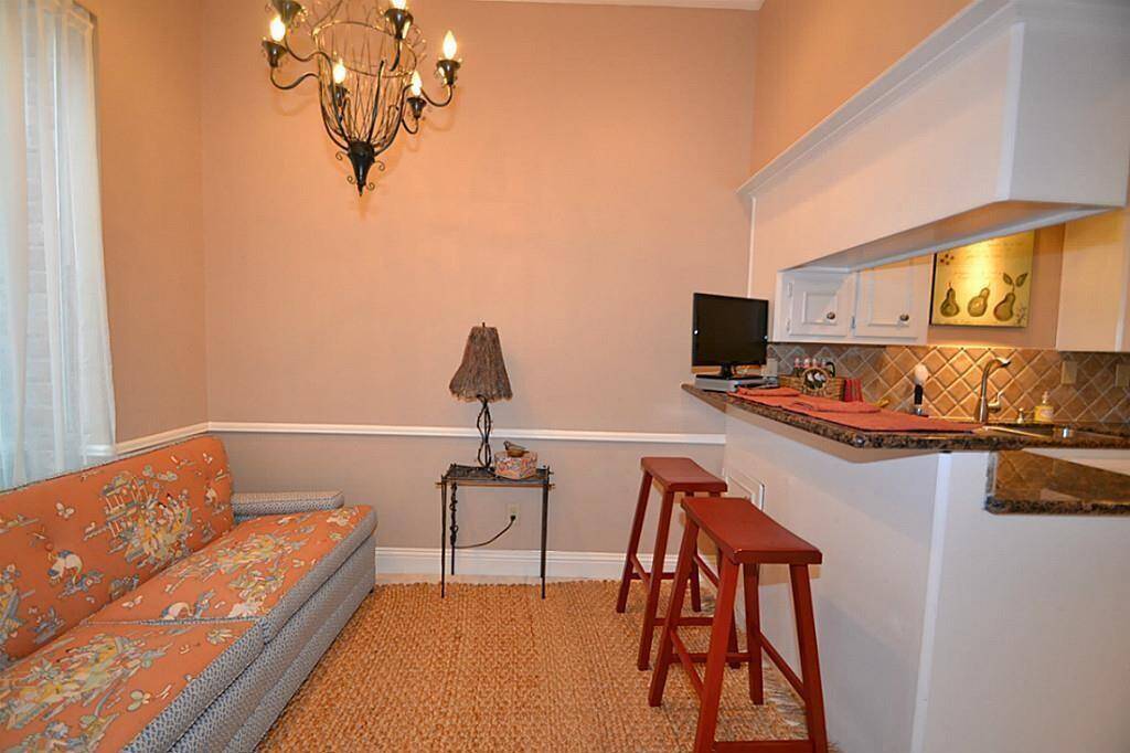 Cozy living space with a warm color palette, featuring a comfortable sofa, stylish chandelier, and a small breakfast bar with seating. Ideal for intimate gatherings or relaxation.