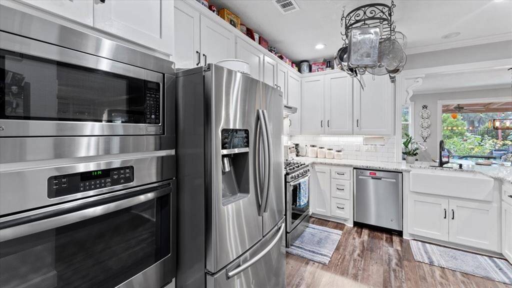 This kitchen features a modern design with stainless steel appliances, white cabinetry, and plenty of counters with space for bar seating. It includes a spacious dining area.