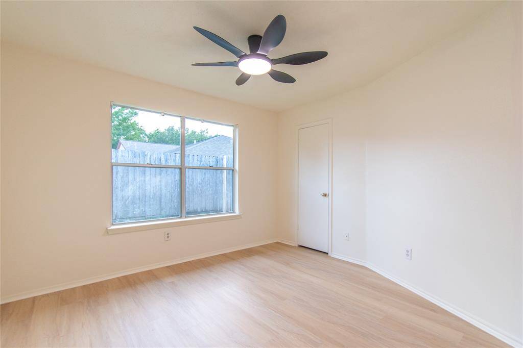 Bedroom 3 with light wood flooring, a ceiling fan, and a large window offering natural light.