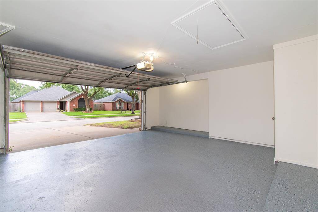 Clean garage with a finished floor and ample lighting. It provides a view of a quiet suburban street with well-maintained homes. Perfect for parking or additional storage space.