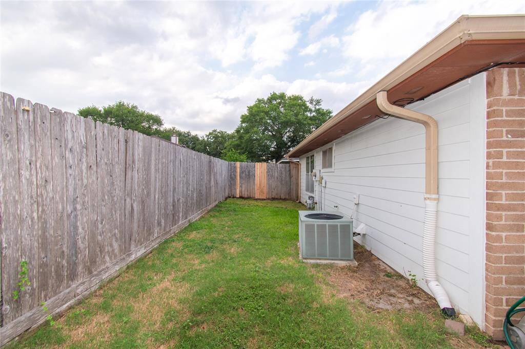 Grassy area, bordered by a wooden privacy fence. The exterior of the house features white siding and brick accent.
