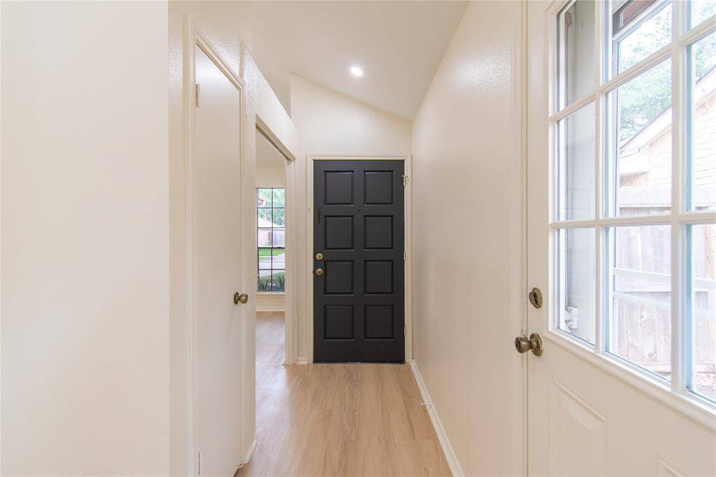 Entryway featuring a dark front door. The space has light walls and new vinyl flooring, with a side window letting in natural light.