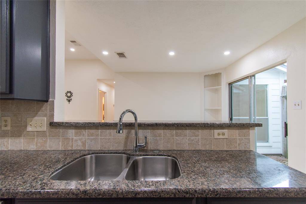 Open layout features recessed lighting and a view into a bright living area with sliding glass doors.