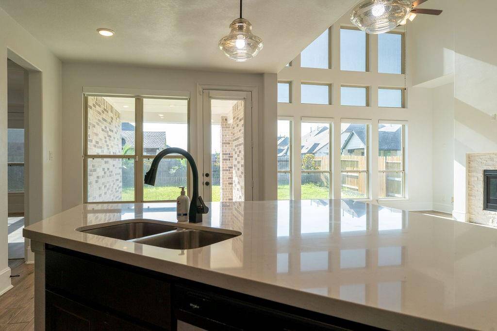 Bright and modern kitchen with a sleek island and sink, open floor plan, large windows for natural light, and a view of the backyard. Perfect for entertaining and family gatherings.