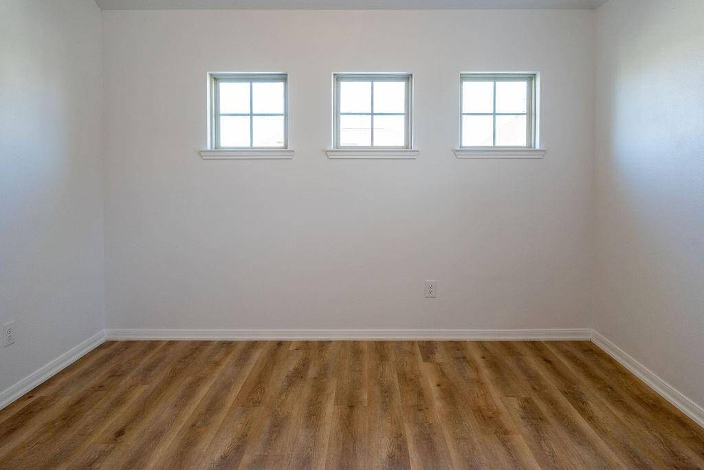 This room features three small square windows, white walls, and wood-look flooring, offering a bright and simple space ideal for customization.