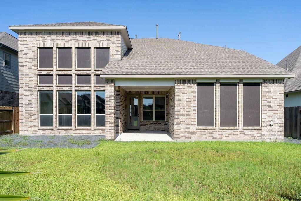 This is a modern brick home with large windows and a well-maintained lawn. The back features a covered patio, perfect for outdoor relaxation.