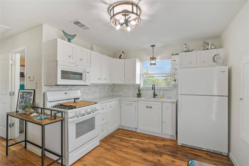 Bright and airy kitchen on the second floor, featuring modern appliances, ample cabinetry, and a stylish light fixture. Perfect for culinary enthusiasts.