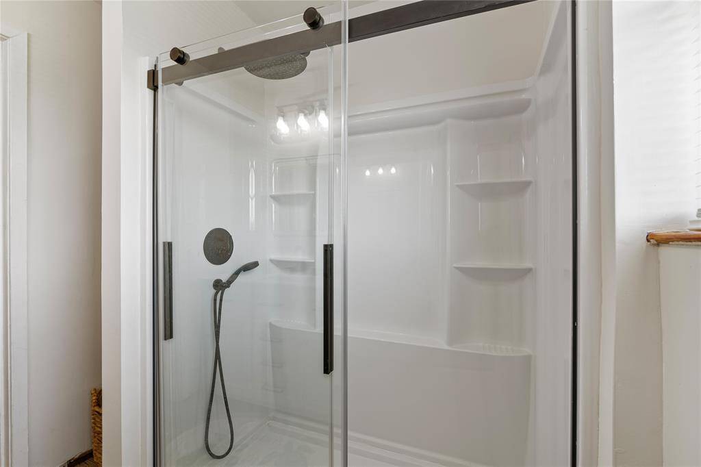 Elevate your daily routine in this sleek second-floor shower, featuring modern fixtures and ample shelving.