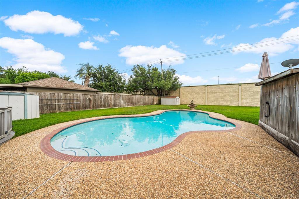 Spacious backyard with in-ground pool, surrounded by a well-maintained lawn and privacy fencing, offering an ideal space for relaxation and outdoor entertainment.