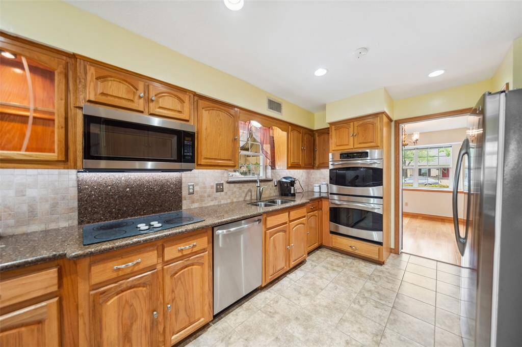 This kitchen offers oak cabinetry, stainless steel appliances, under cabinet lighting and a stylish tile backsplash. This kitchen boasts a built-in microwave, built in wine refrigerator, double oven, and electric cooktop.