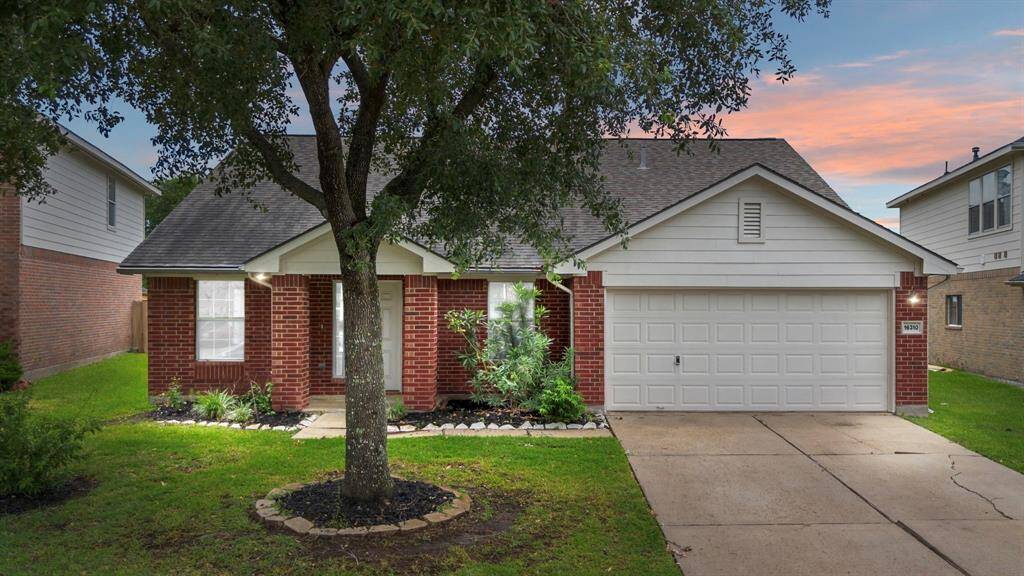 Charming single-story home with a two-car garage. The front yard features a mature tree, creating a welcoming curb appeal.