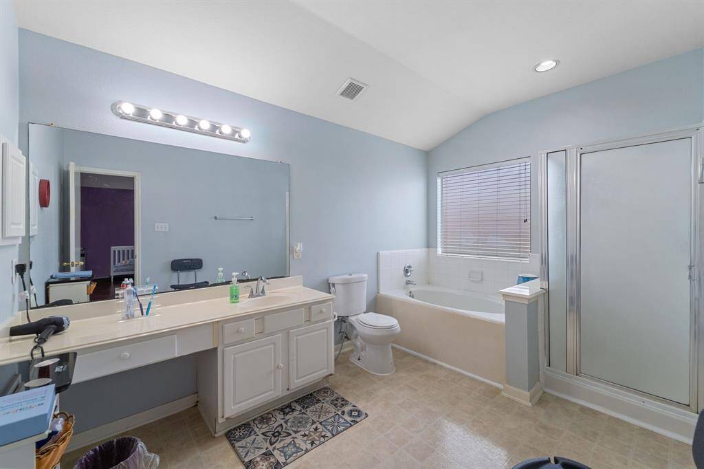 This spacious bathroom features a large vanity with counter space, a wide mirror, a separate shower, and a bathtub.  Has a window for natural light.