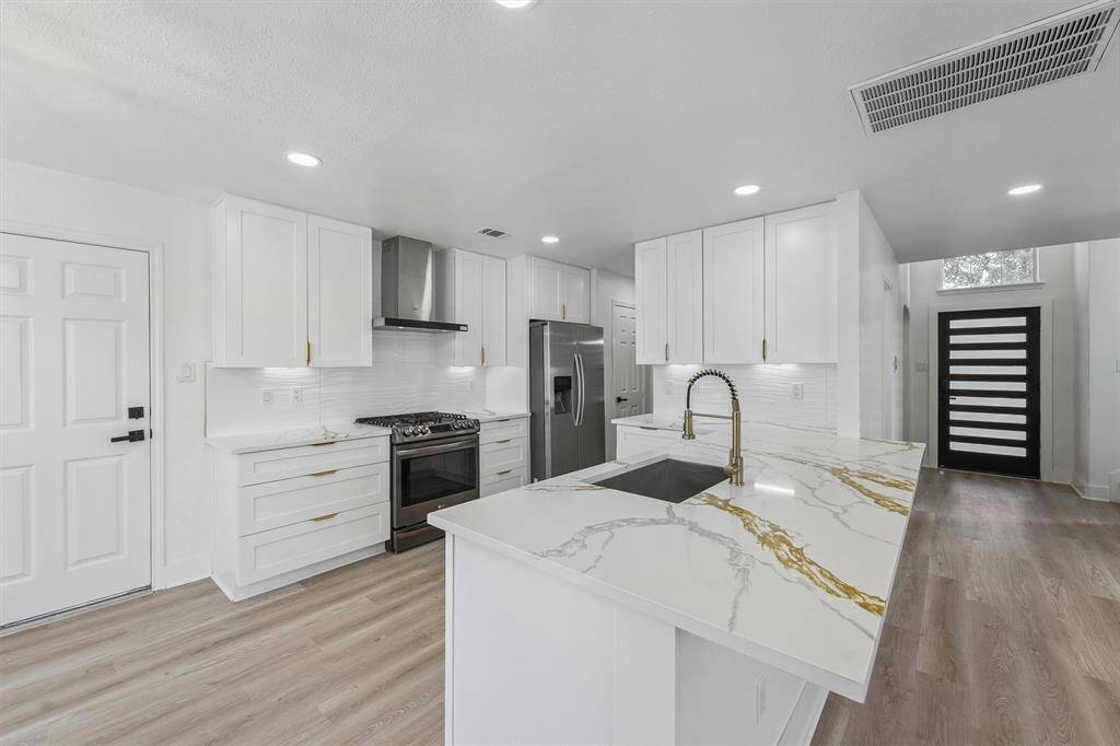 Bright and stylish kitchen featuring ample natural light, sleek cabinetry with gold hardware, and modern under-cabinet lighting that adds both function and ambiance. A beautiful blend of elegance and practicality that complements the home’s overall design.