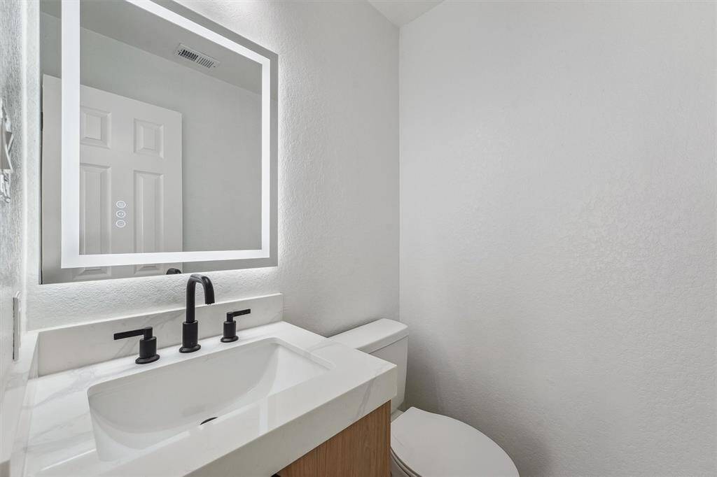 The downstairs half bath is a must-see, featuring a sleek, modern design with a statement mirror enhanced by mood LED lighting—offering both style and sophistication for your guests.