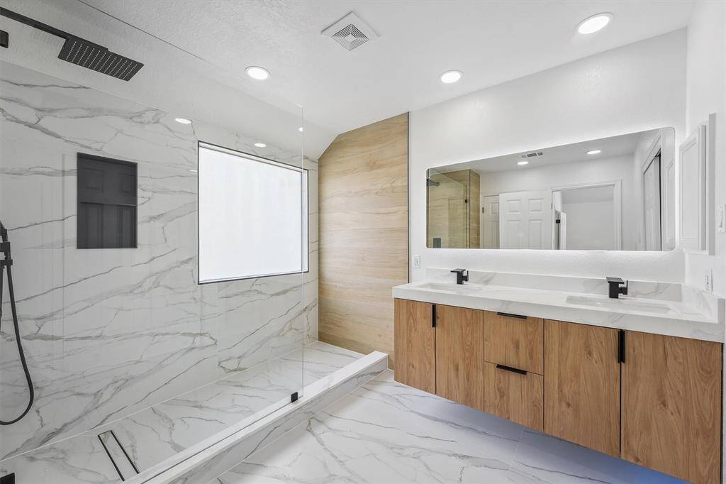 The spa-inspired master bathroom showcases an enormous walk-in shower, double vanity, and a sleek LED mirror with built-in defogger. Floating cabinets with mood lighting underneath add a luxurious, modern touch—perfect for starting or ending your day in style.