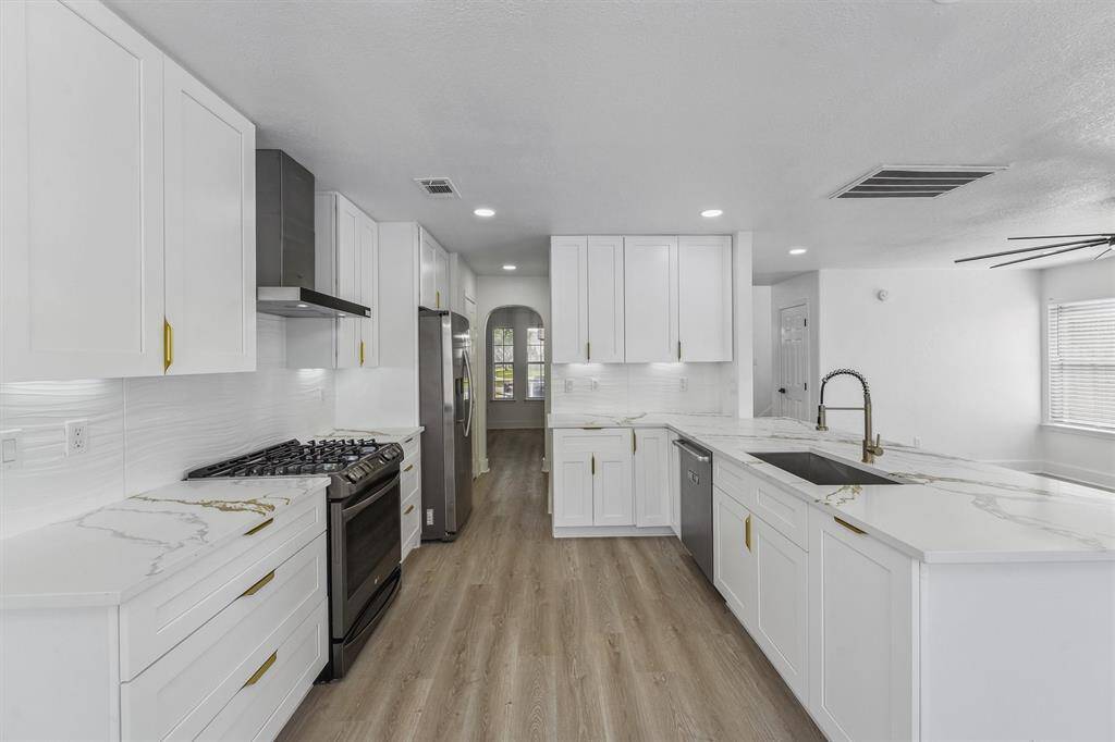 Highlighting sleek quartz countertops, stainless steel appliances, and a touchless vent hood for modern convenience.