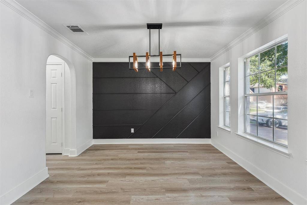 The formal dining room is perfectly sized for gatherings, featuring a stunning accent wall, abundant natural light from large windows, and a modern light fixture that adds a contemporary touch to this elegant space.
