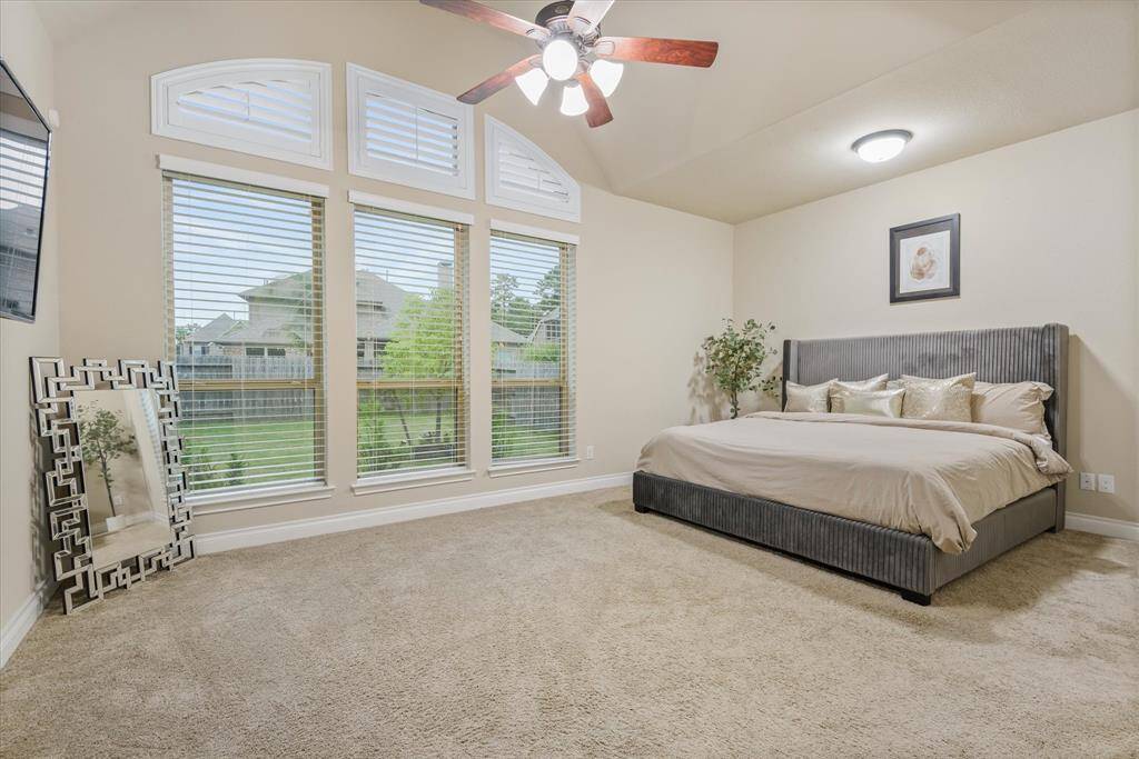 Spacious master bedroom with soft carpet, large windows, and a serene atmosphere perfect for rest and relaxation.