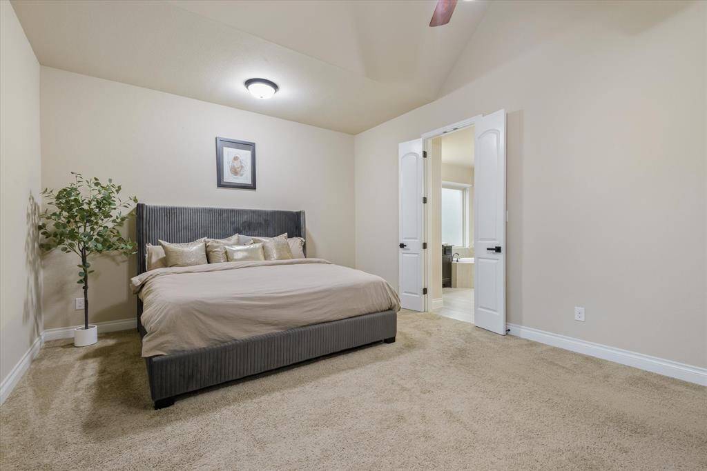 Master bedroom captured from a new angle, showcasing its generous size, natural light, and cozy carpeted floor.
