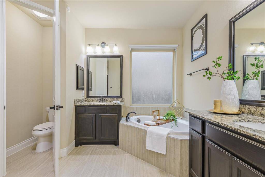 Elegant master bathroom featuring double vanities, a private water closet, and a relaxing soaking tub.